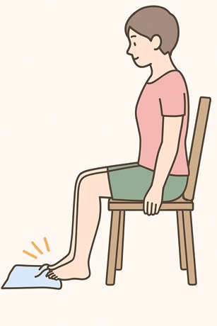 椅子に座り床に置いたタオルを足の指で手繰り寄せる人